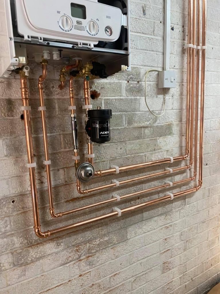 Wall mounted boiler with copper pipes showing