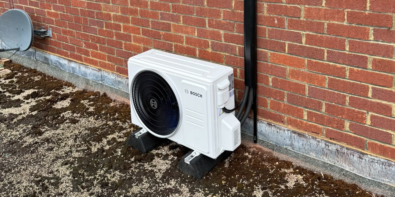 Air conditioning unit at the base of a brick wall