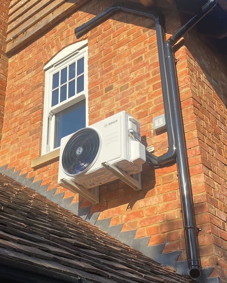 Air conditioning unit on side of house next to window