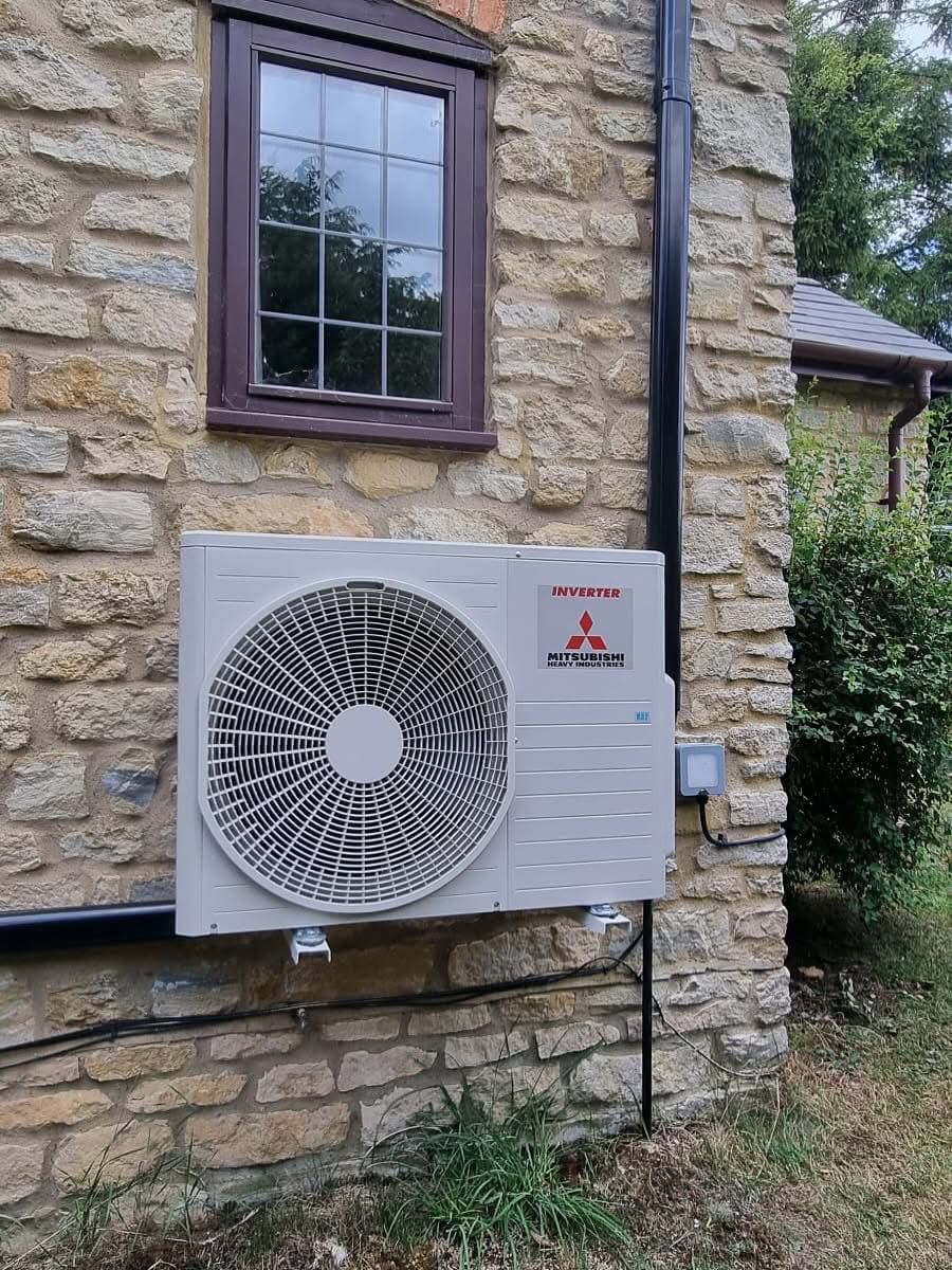 Air conditioning unit on side of brick house underneath window